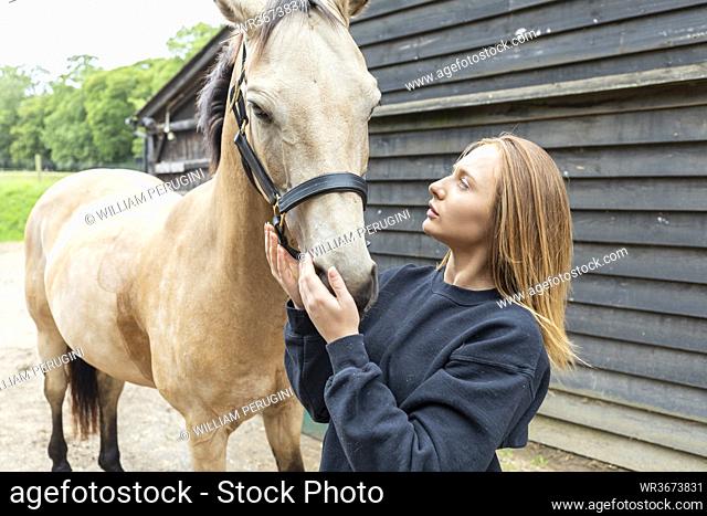 Young woman stroking her horse