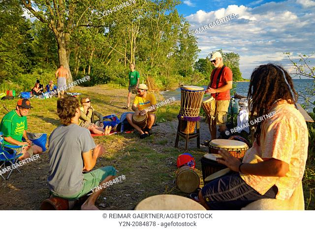 Group playing in a drum circle at Hanlan's Point beach Toronto at sunset