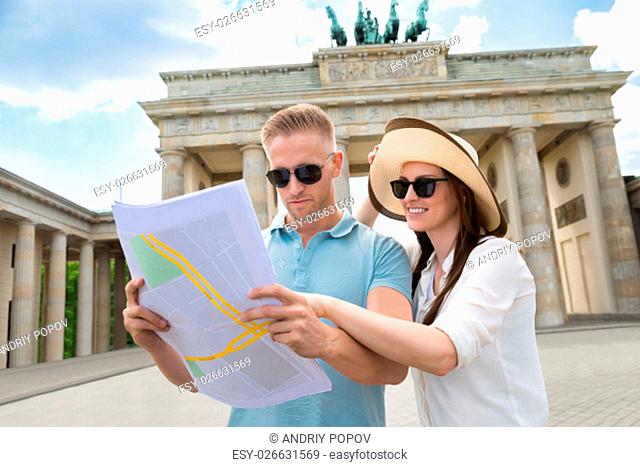 Young Couple Looking At Map In Front Of Brandenburg Gate