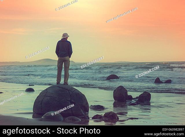 Tourist on unusual Moeraki Boulders, Koekohe beach, Otago, South Island, New Zealand