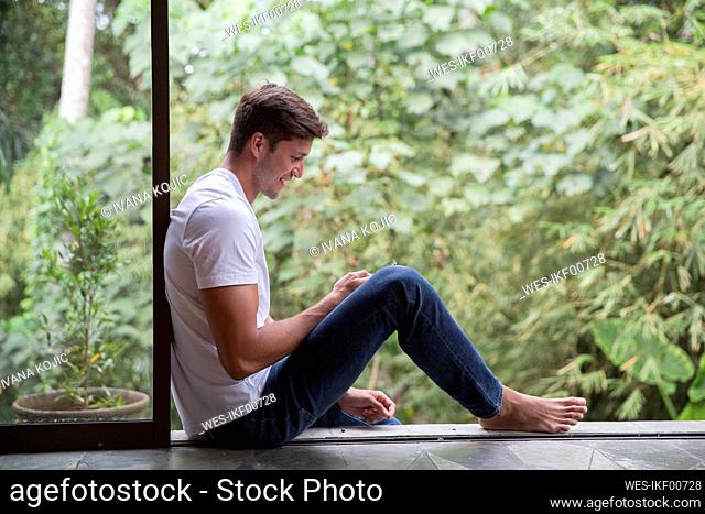 Happy young man using smart phone at home