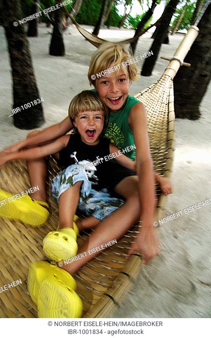 Children playing in a hammock in Baros Resort, The Maldives, Indian Ocean