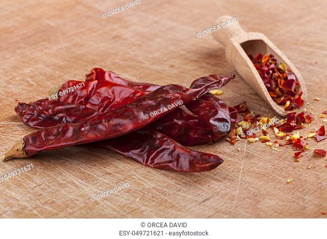 Dry red hot chili peppers with wooden spoon on brown wood background