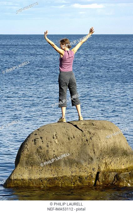 A woman standing on a cliff by the sea, Vaddo, Stockholm archipelago, Sweden