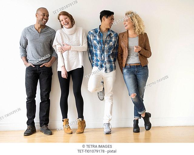 Laughing friends standing against white wall