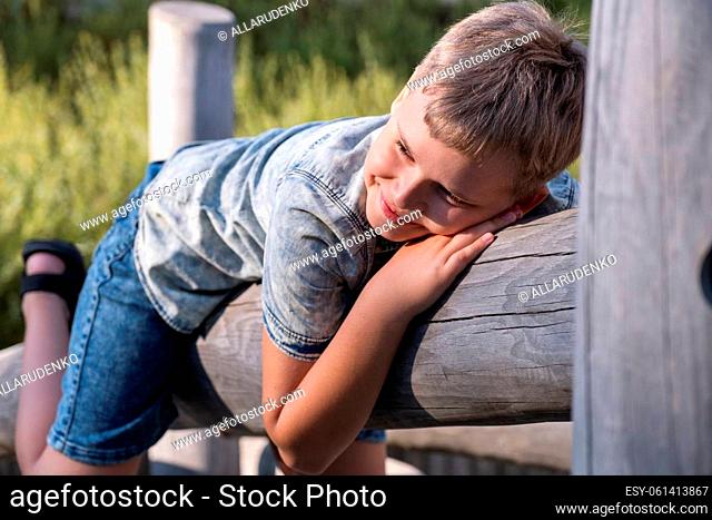 Cheerful and mischievous boy having fun at a wooden playground outdoors