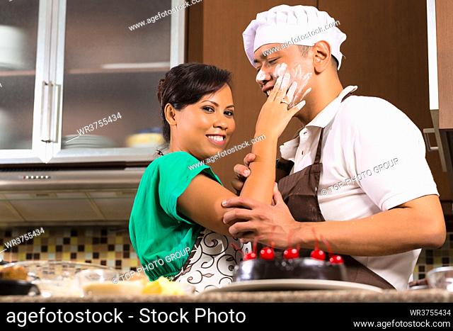 Asian couple in kitchen teasing each other while baking