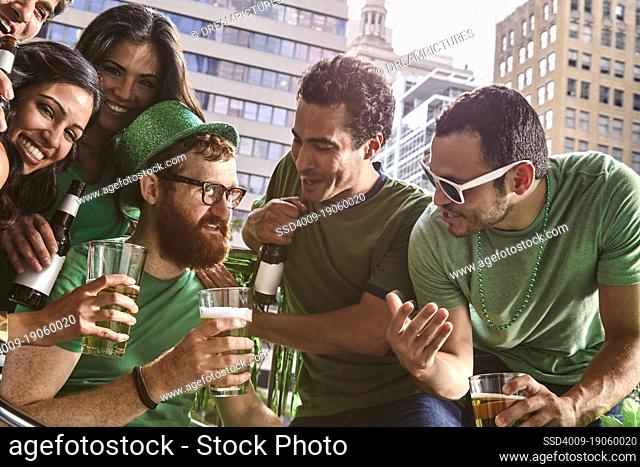 Group of diverse friends toasting while drinking beer and celebrating St Patrick's Day