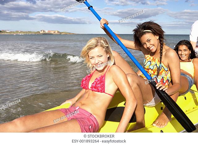 Teenage girls in sea with canoe