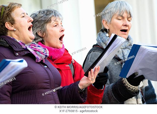 A group of women singing christmas carols on the main street in Aberystwyth collecting to raise money for charity, Wales UK