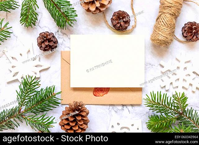 Winter Christmas Composition with a card over sealed envelope flat lay. Christmas and New Year greeting card template with fir tree branches, pine cones