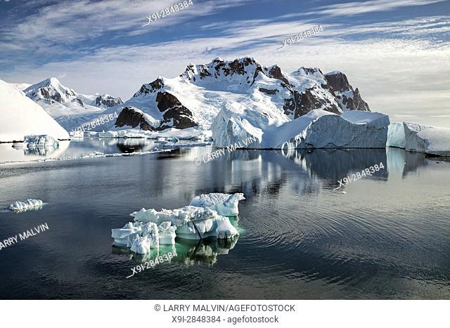 Iceberg in the waters of the Lemaire Channel with mountains and glaciers along the Antarctic Peninsula