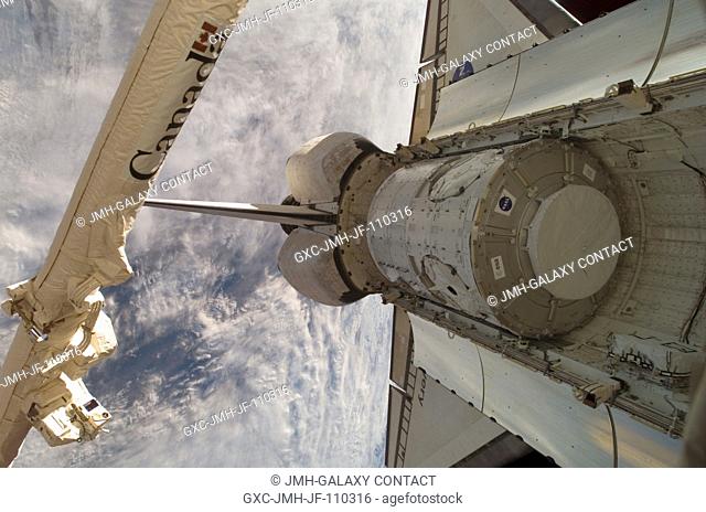 Backdropped by a cloud-covered portion of Earth, the Harmony node in Space Shuttle Discovery's cargo bay is featured in this image photographed by an Expedition...