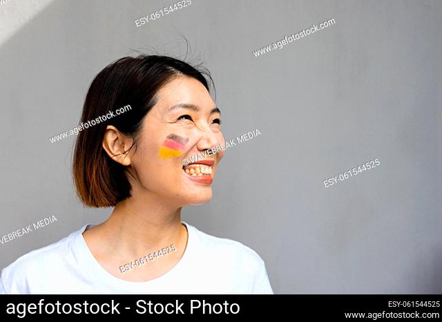 Happy asian woman with flag of germany on her cheek