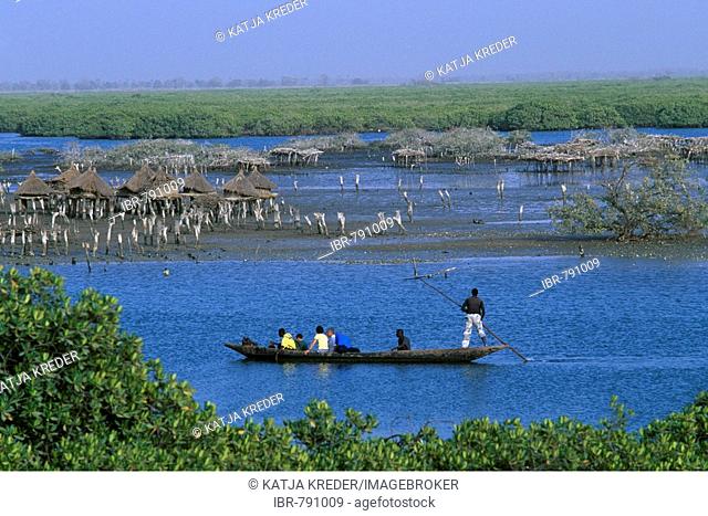 Canoe passing storage houses at Joal-Fadiouth, Senegal, Africa