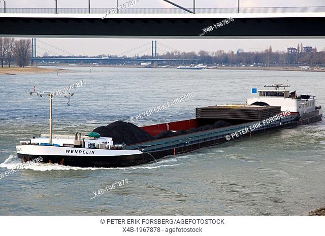 Barge flat bottomed cargo transpot boat on River Rhine in front of central Dusseldorf city North Rhine Westphalia region western Germany Europe
