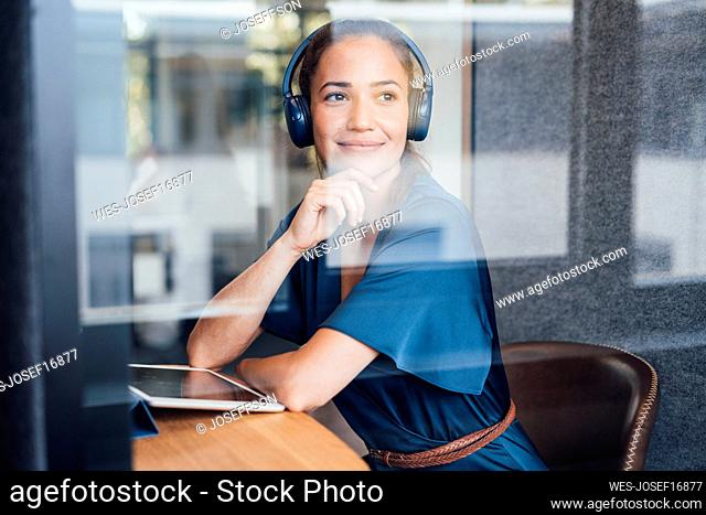 Thoughtful businesswoman wearing headset in soundproof cabin