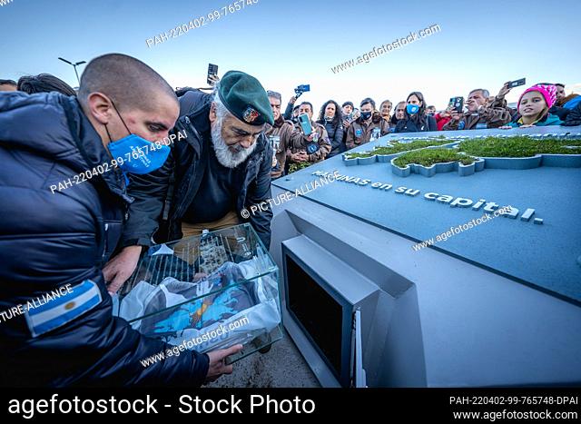 01 April 2022, Argentina, Ushuaia: Eduardo Cequeira (r), Argentine frigate captain, and his son (l) place a glass capsule containing documents related to the...