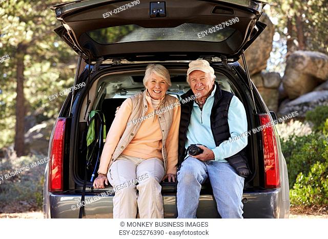 Senior couple sit in open car trunk before a hike, close-up