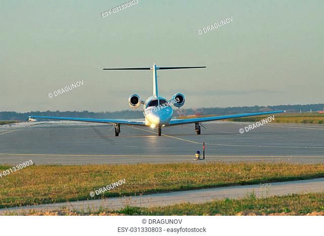 Private business jet taxiing along the runway to take off or after landing on sunset