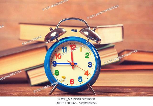 Alarm clock and books on wooden table
