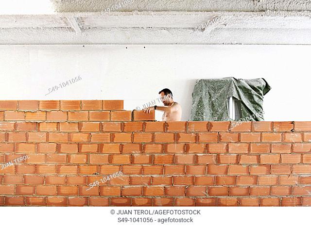 man working in a wall of bricks