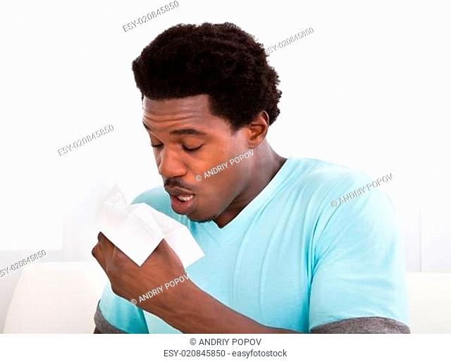 Young Man Blowing His Nose In A Tissue