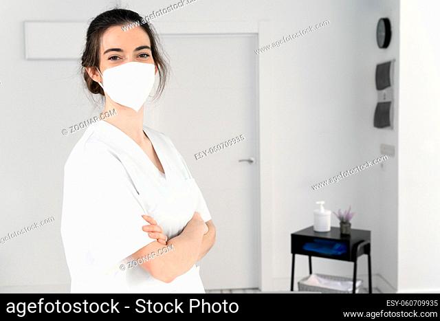 Friendly female physiotherapist posing in modern clinic wearing protective face mask during coronavirus pandemic. High quality photo