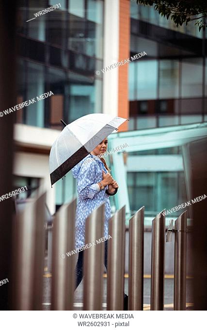 Beautiful woman holding umbrella and walking on street