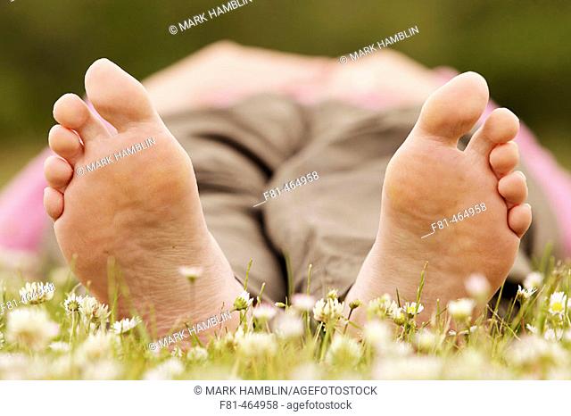 Close-up of undersides of bare feet of woman lying on grass