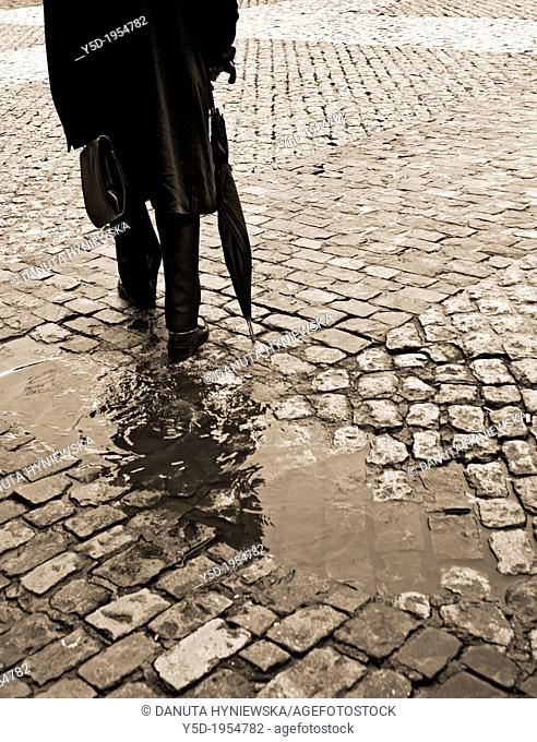 lonely man in long coat walking with umbrella and briefcase, sidewalk, paving stones, after rain, sepia, old fashioned, actually Madrid, Spain, Europeans