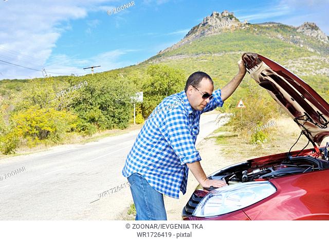 Adult man is standing near his broken car