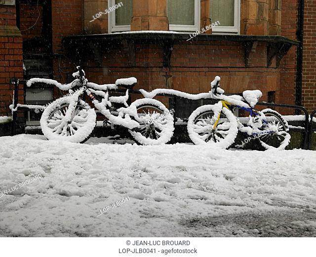 England, East Sussex, Hove, Two bicycles covered in snow leaning against railings in Hove