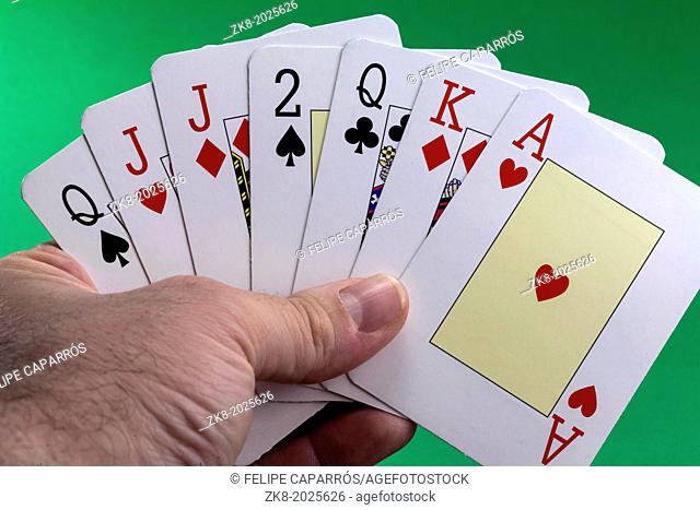 Hand holding a royal flush hearts on green