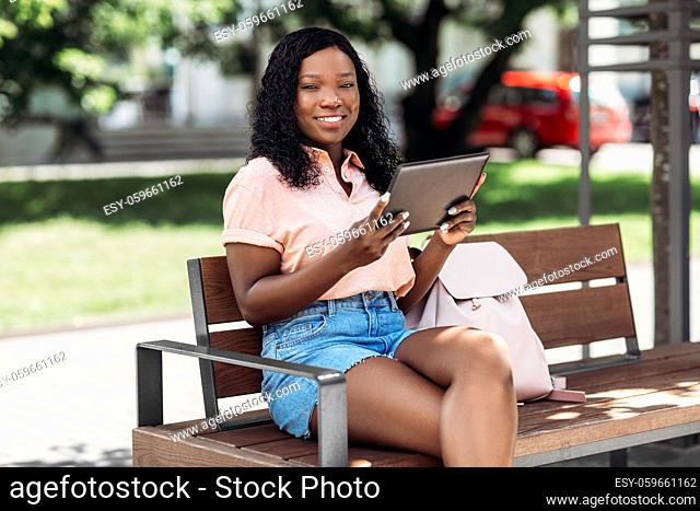african american woman with tablet pc in city