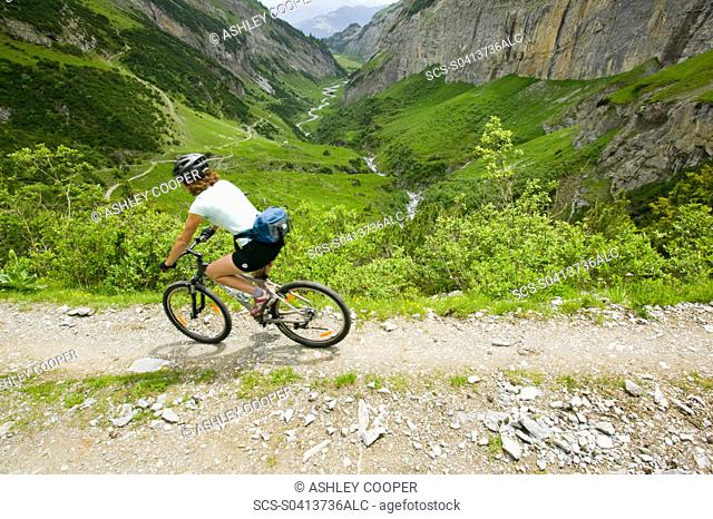A women mountain biking in a high Alpine valley at Bargis in Switzerland