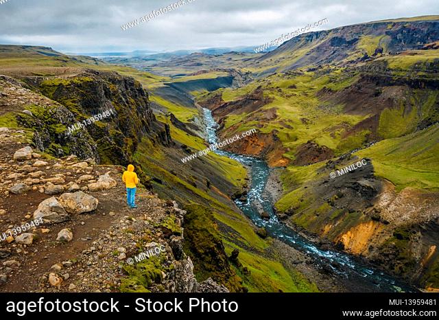 Aerial view of man enjoying Iceland landscape of highland valley and river Fossa with blue water stream and green hills and moss covered cliffs