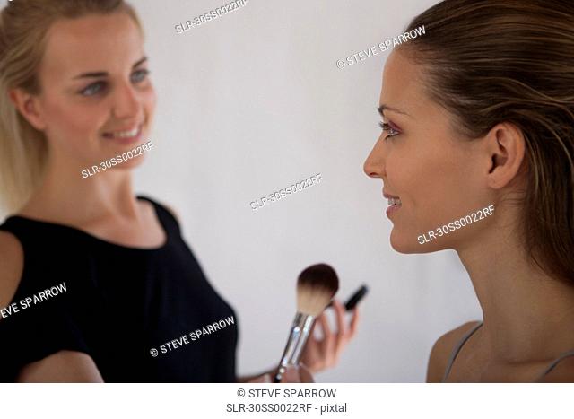 Makeup artist applying blush to model