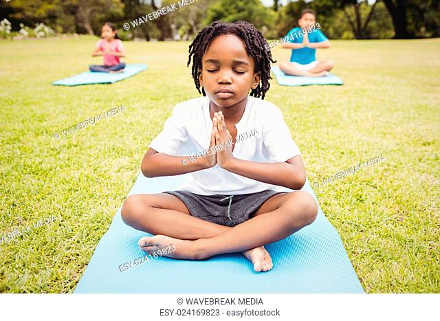 Close up on a young boy doing yoga with other children