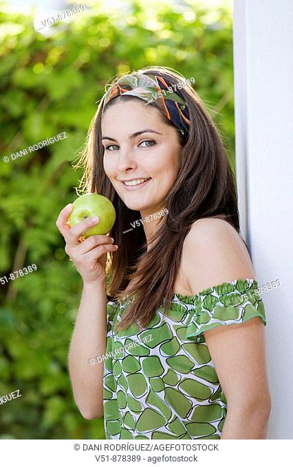 Woman with an apple outdoor looking at camera
