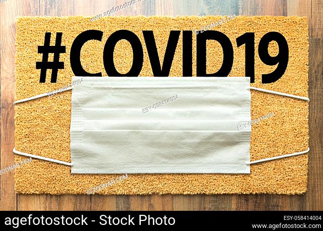 Welcome Mat With Medical Face Mask and #COVID19 Text Amidst The Coronavirus Pandemic