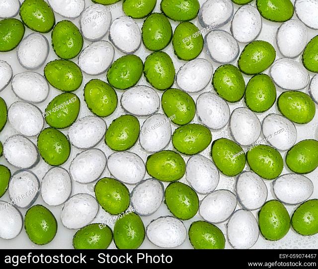 artificial round stones with water drop of green and white color, top view. imitation pebbles