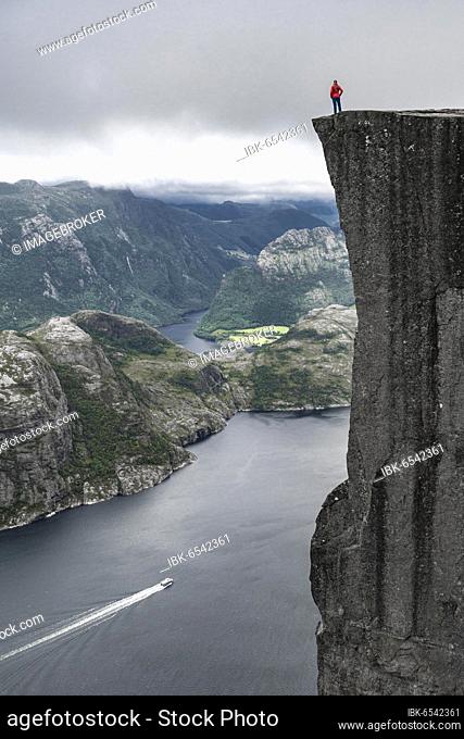Person standing on steep cliff, Preikestolen rock spire, Lysefjord, Ryfylke, Rogaland, Norway, Europe