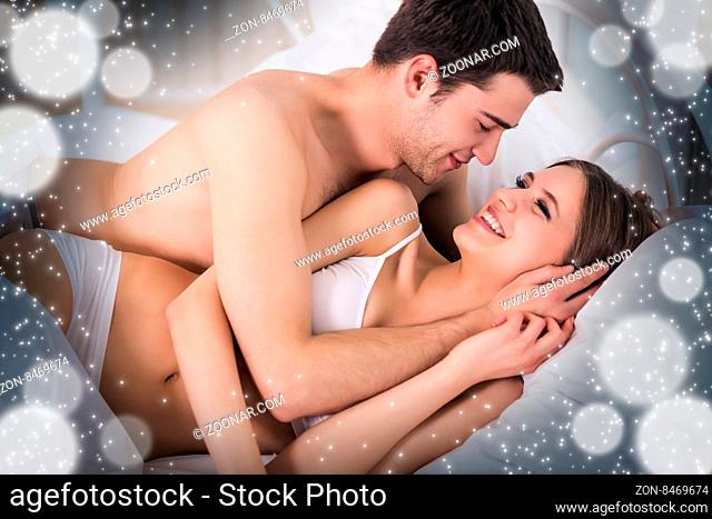 Beautiful young loving couple lying in bed and looking at each other