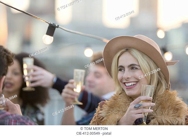 Smiling young woman drinking champagne at party