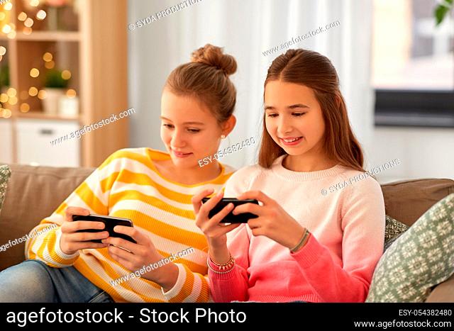 happy teenage girls with smartphones at home