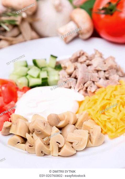 salad from sliced vegetables, meat and champignon with garnish on plate