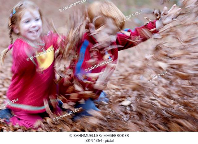 Children are playing in autumn foliage leaves