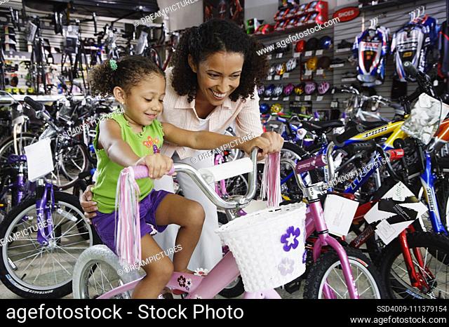 Mother helping young daughter with bike in bike shop