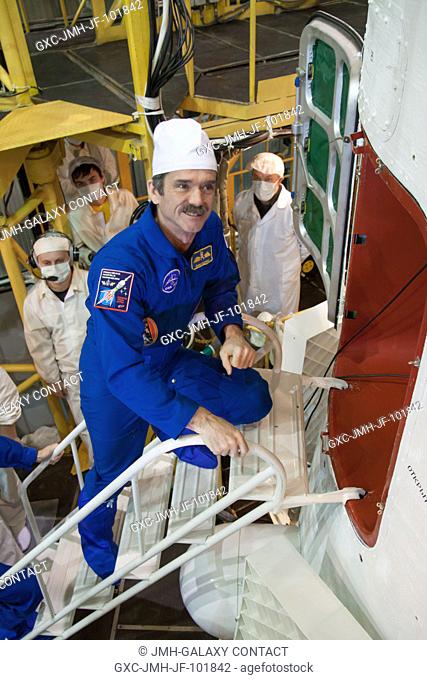 At the Integration Facility at the Baikonur Cosmodrome in Kazakhstan, Expedition 34 Flight Engineer Chris Hadfield of the Canadian Space Agency climbs aboard...